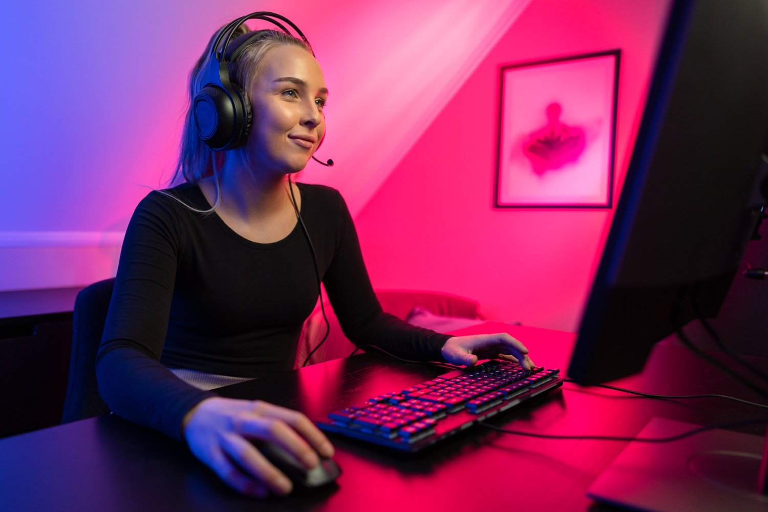 Happy Pretty Blonde Gamer Girl Playing Online Video Game on Her Personal Computer.